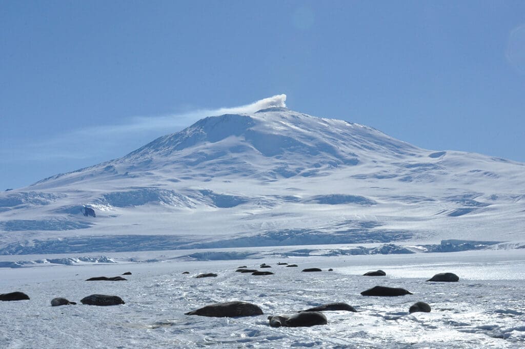 Snow-covered mountain with smoke at the peak