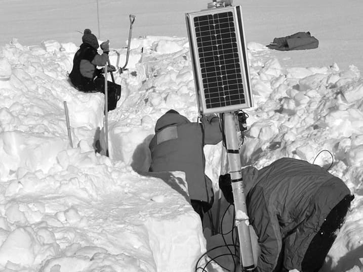 Researchers installing solar panel in snowy field