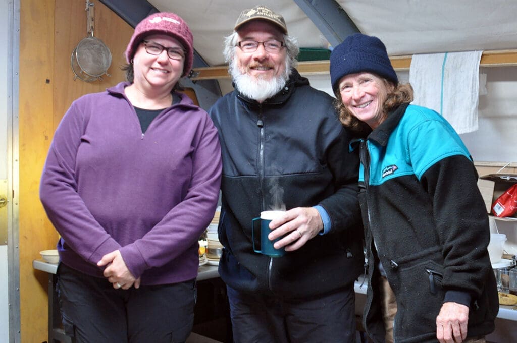 Three people enjoying hot drinks indoors.